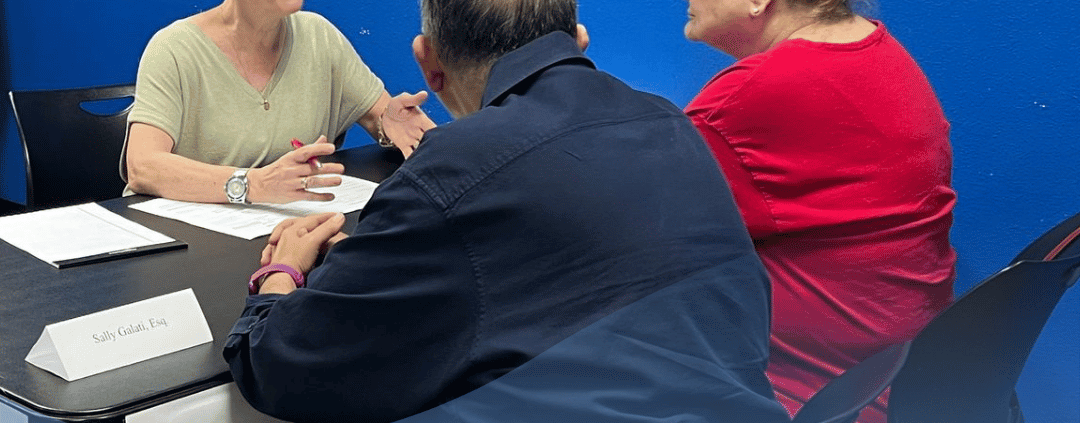 Older couple, sitting down across an attorney, filling out their Health Care Power of Attorney.